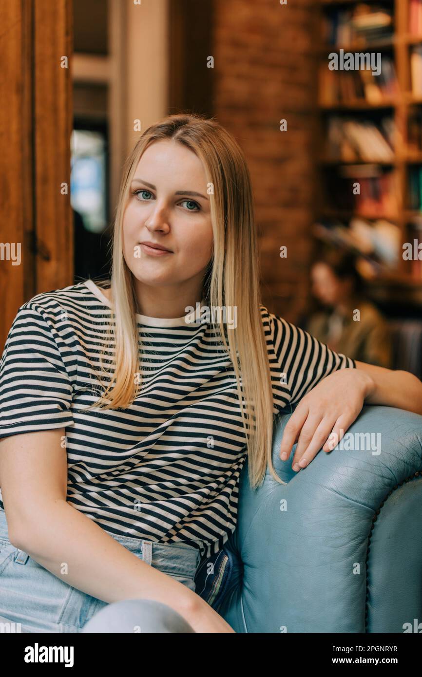 Eine Frau mit blonden Haaren, die im Café auf der Couch sitzt Stockfoto