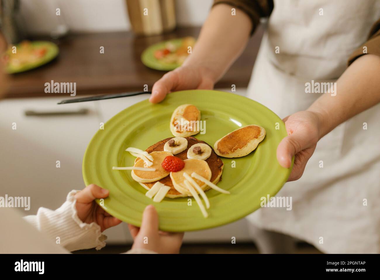 Vater und Tochter halten zu Hause süße Osterhasen-Pfannkuchen Stockfoto