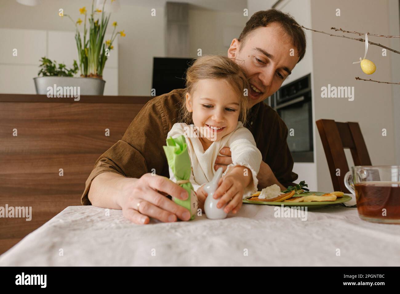 Vater und Tochter spielen zu Hause mit Osterei und Häschen Stockfoto