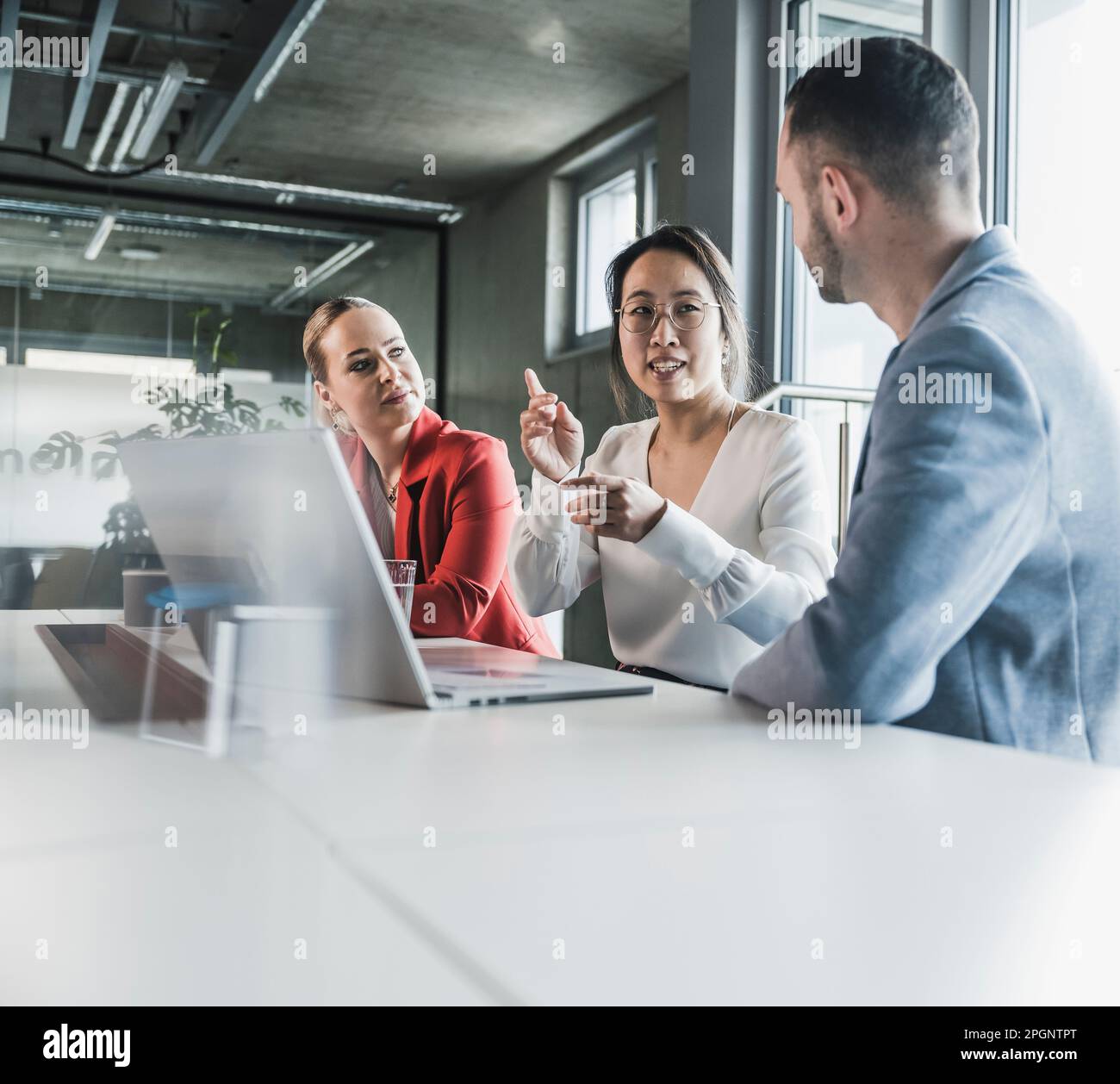 Geschäftsfrau, die Kollegen durch Gesten bei einem Meeting im Büro erklärt Stockfoto