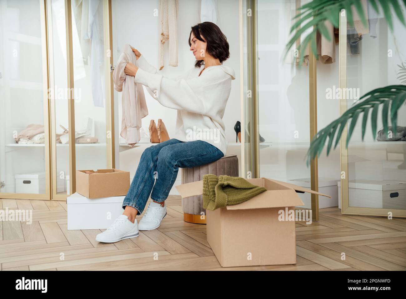 Eine junge Frau, die Kleidung für das Recycling zu Hause aussucht Stockfoto