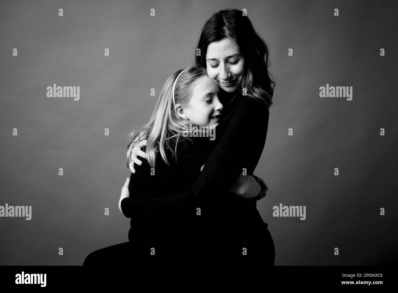 Lächelnde Mutter und Tochter umarmten sich mit geschlossenen Augen Stockfoto