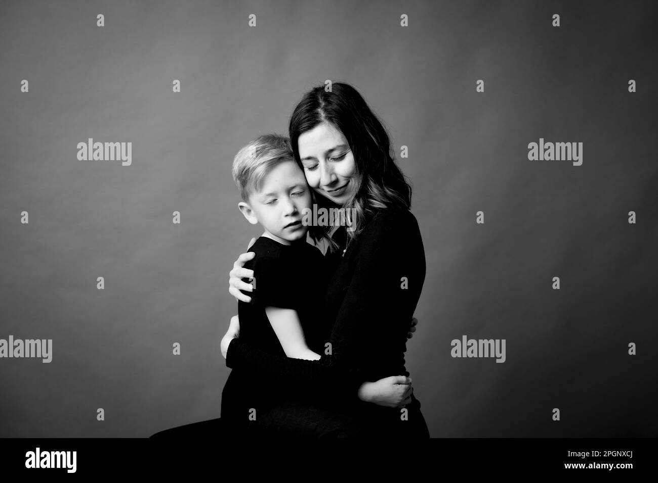 Liebevolle Mutter und Sohn umarmen sich mit geschlossenen Augen Stockfoto