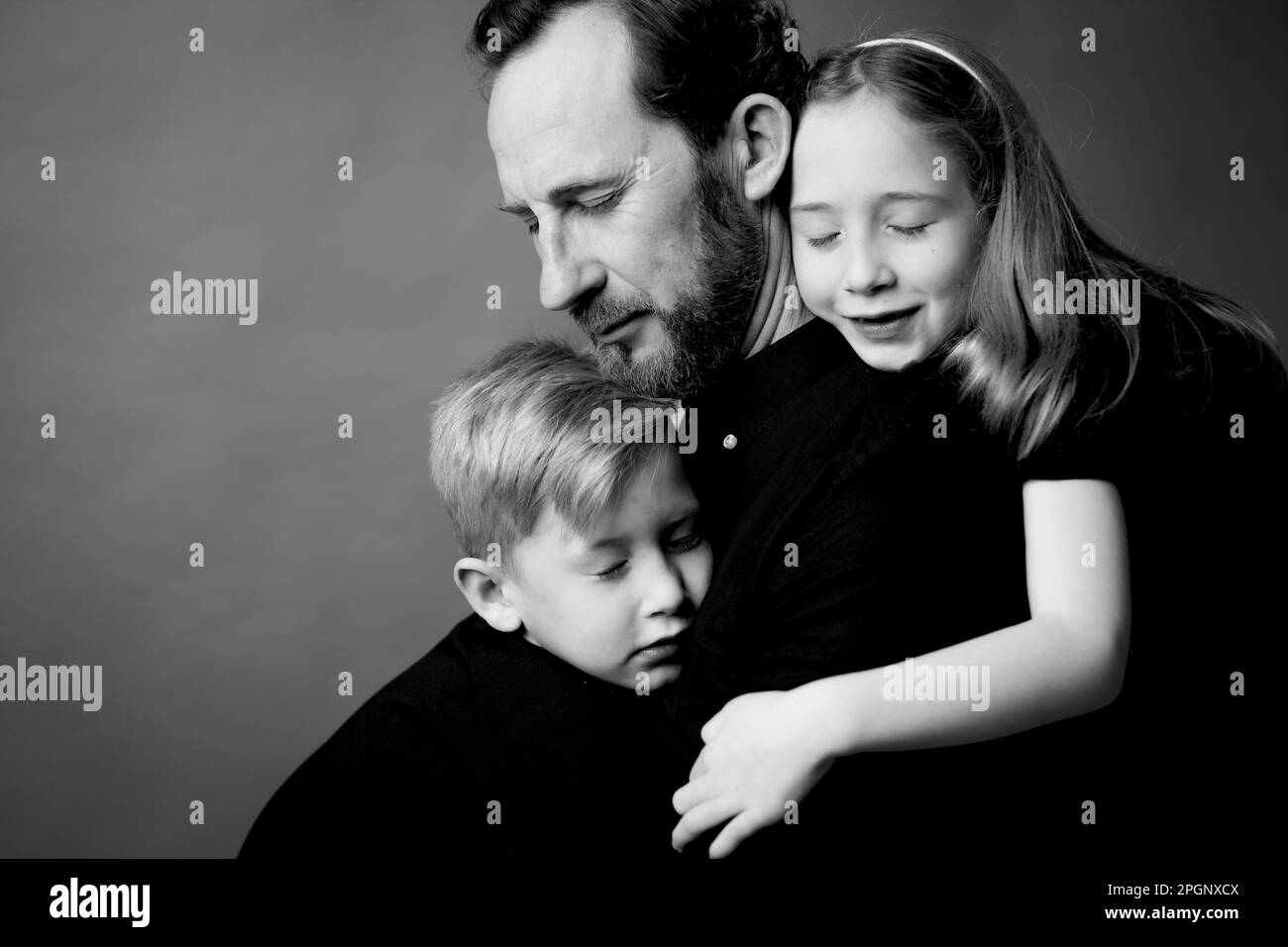 Vater und Kinder umarmen sich mit geschlossenen Augen Stockfoto