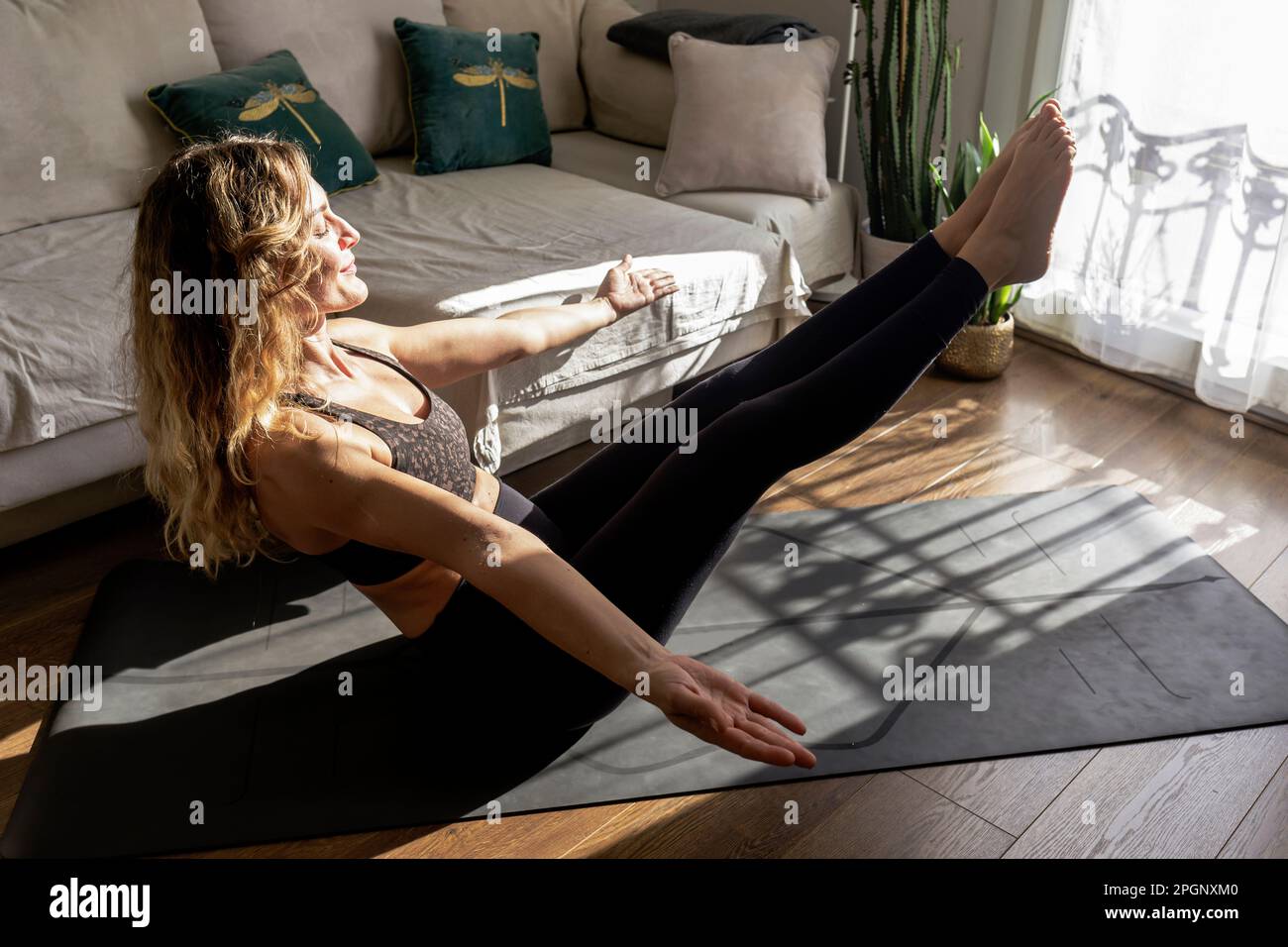 Frau mit geschlossenen Augen, die zu Hause Yoga auf Matte im Wohnzimmer praktiziert Stockfoto