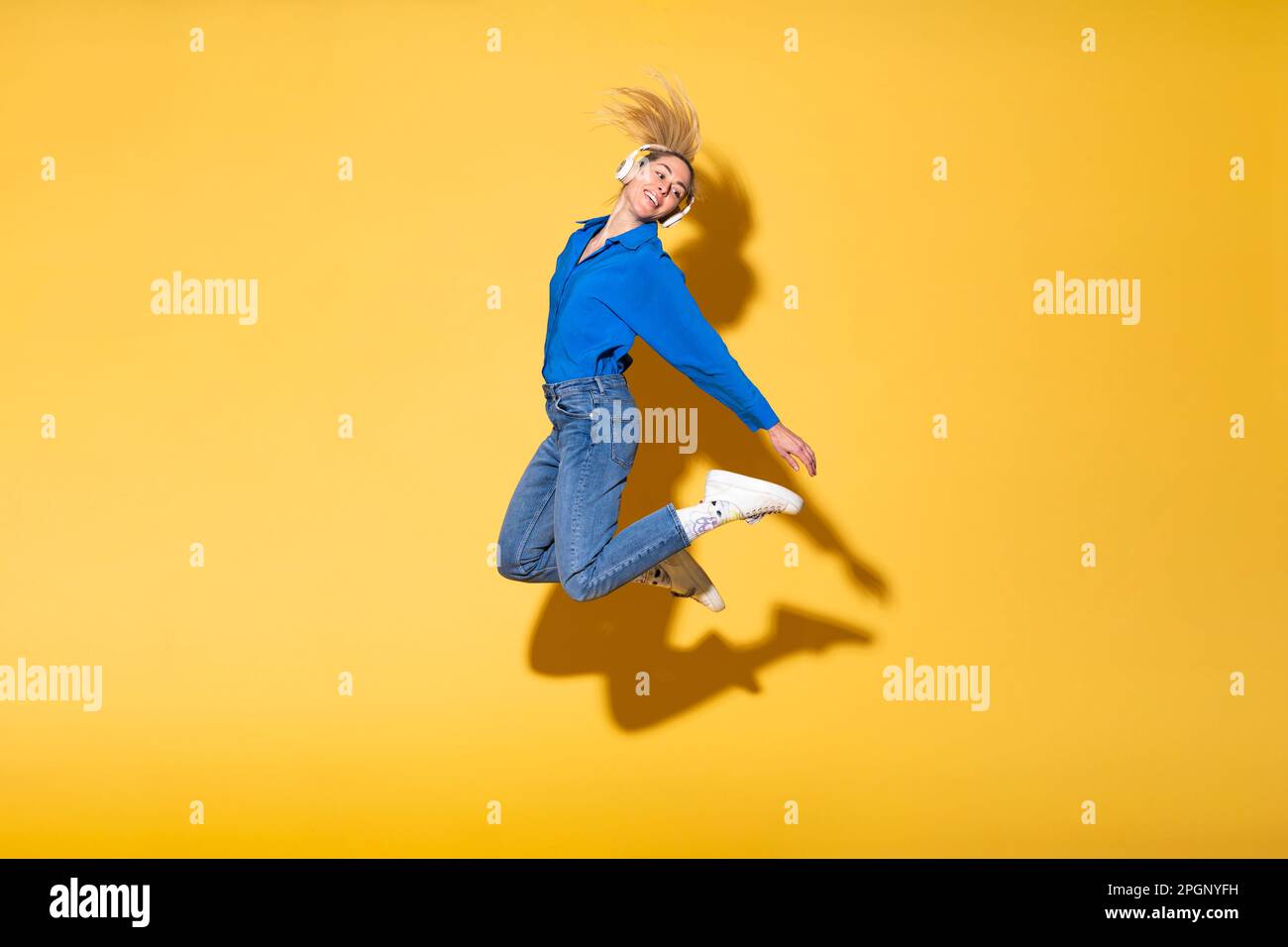 Sorglose Frau, die vor Freude vor gelbem Hintergrund springt Stockfoto