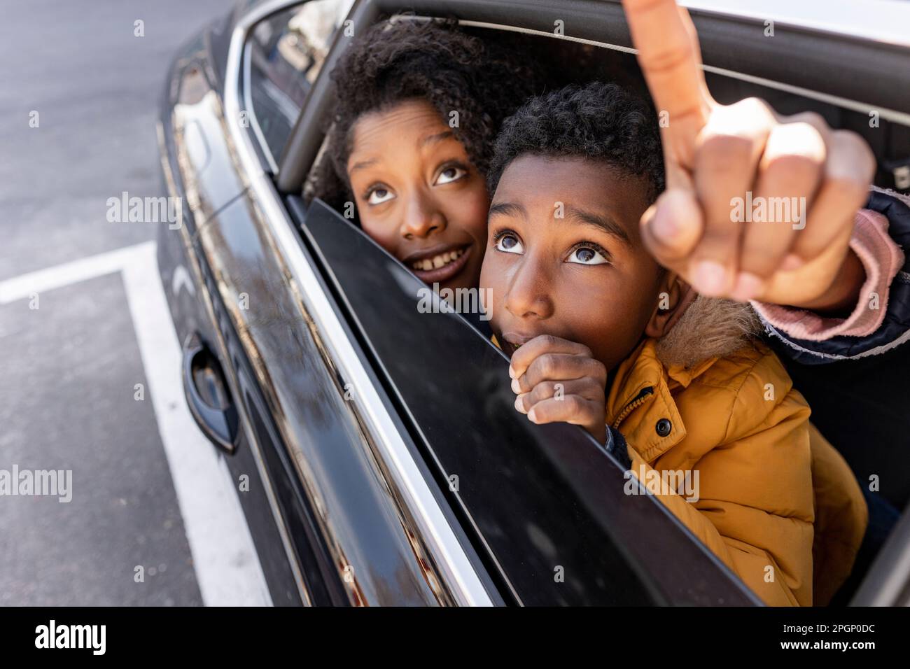 Ein Junge mit Mutter, der durch das Fenster zeigt und mit dem Auto fährt Stockfoto