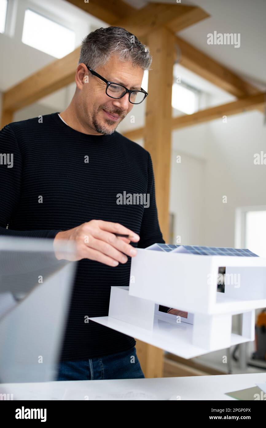 Lächelnder Designexperte, der das Modell auf der Baustelle untersucht Stockfoto