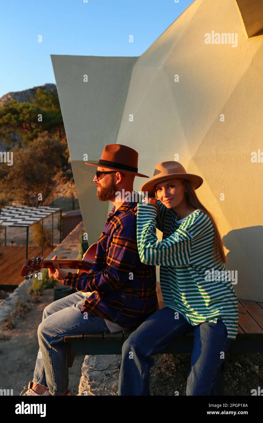 Ein Hipster-Paar, das bei Sonnenuntergang in der Nähe des Öko-Hauses sitzt Stockfoto