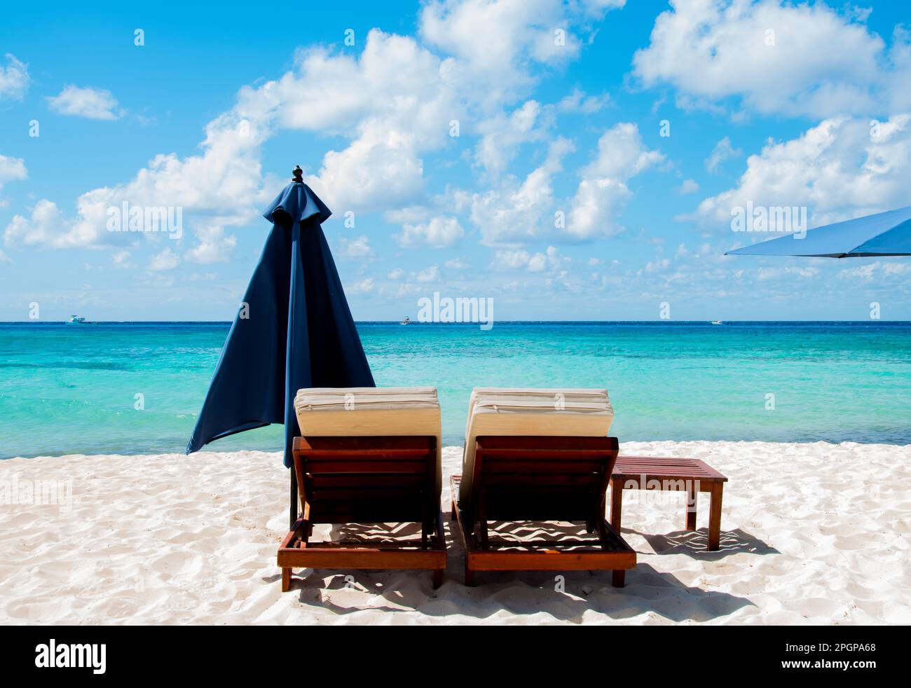 Zwei Sonnenliegen, ein Tisch und ein Sonnenschirm vor dem Meer Stockfoto