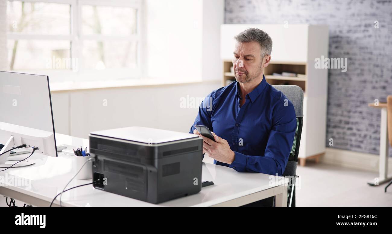 Geschäftsmann, Der Im Büro Druckbefehle Auf Einem Smartphone Ausgibt Stockfoto