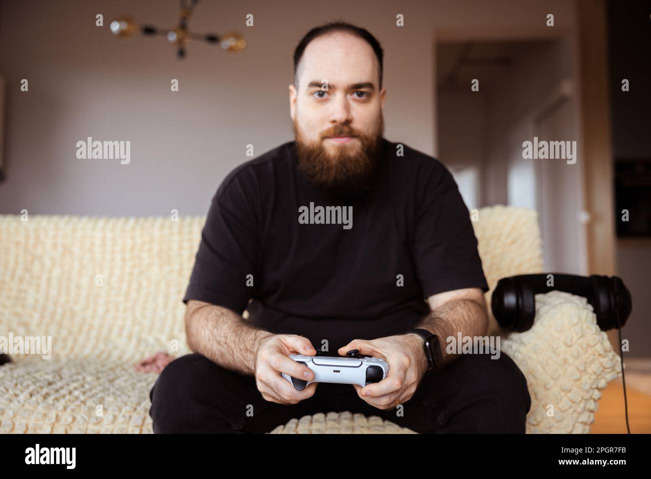 Fokussierter männlicher Gamer, komplett in schwarzer Kleidung gekleidet, mit einem Controller in der Hand. Lifestyle in einer virtuellen Welt Stockfoto