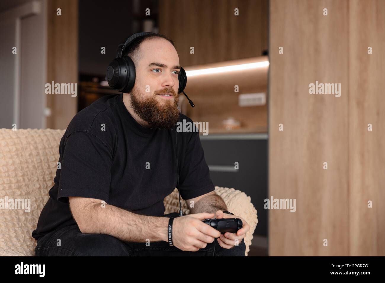 Männlicher Gamer, der Videospiele auf der Konsole spielt, mit dem Controller in der Hand. Und seine Headsets an. Gesichtsausdruck eines Spielers. Stockfoto