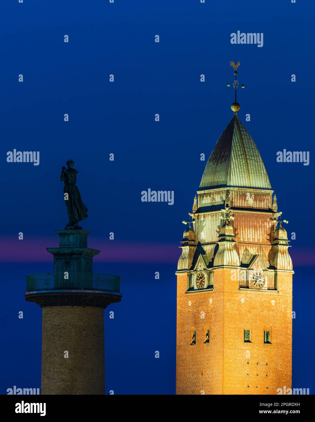 Der majestätische Turm einer alten Kirche ragt am Nachthimmel zusammen mit einer Statue auf dem Turm. Stockfoto