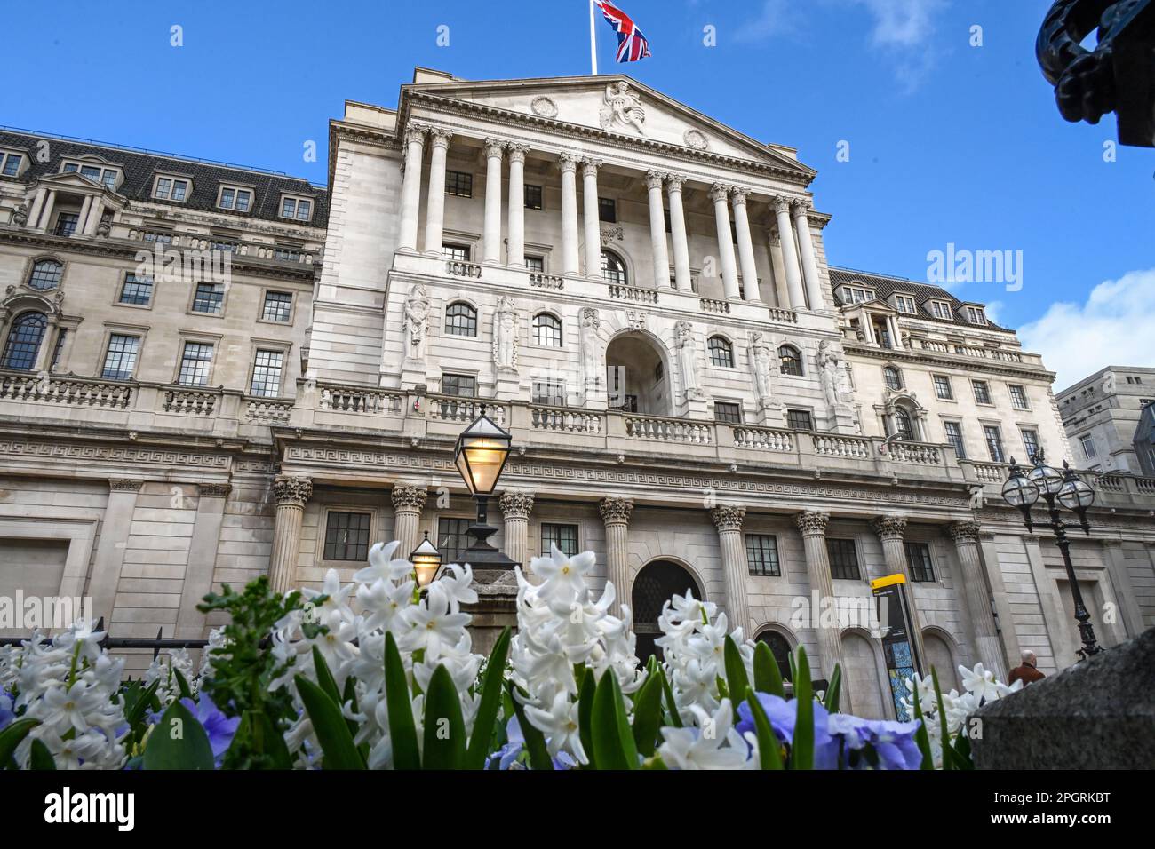 Das Bank of England Gebäude BoE, Threadneedle Street, London, Großbritannien, Fassade mit Frühlingshyazinthen und Stiefmütterchen im Vordergrund Stockfoto