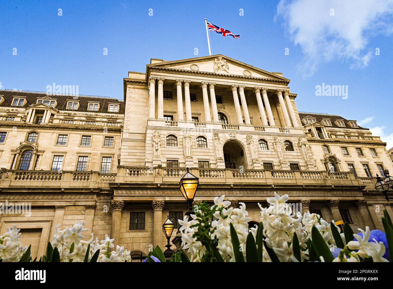 Das Bank of England Gebäude BoE, Threadneedle Street, London, Großbritannien, Fassade mit Frühlingshyazinthen und Stiefmütterchen im Vordergrund Stockfoto