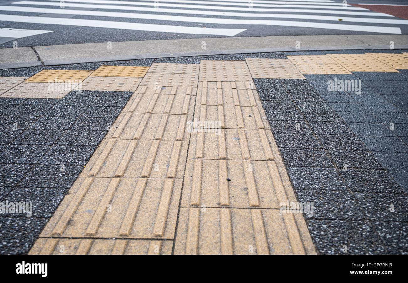 Japanisch gelber Tenji blockiert oder taktile Pflasterarbeiten an einer Kreuzung in Tokio, Japan Stockfoto