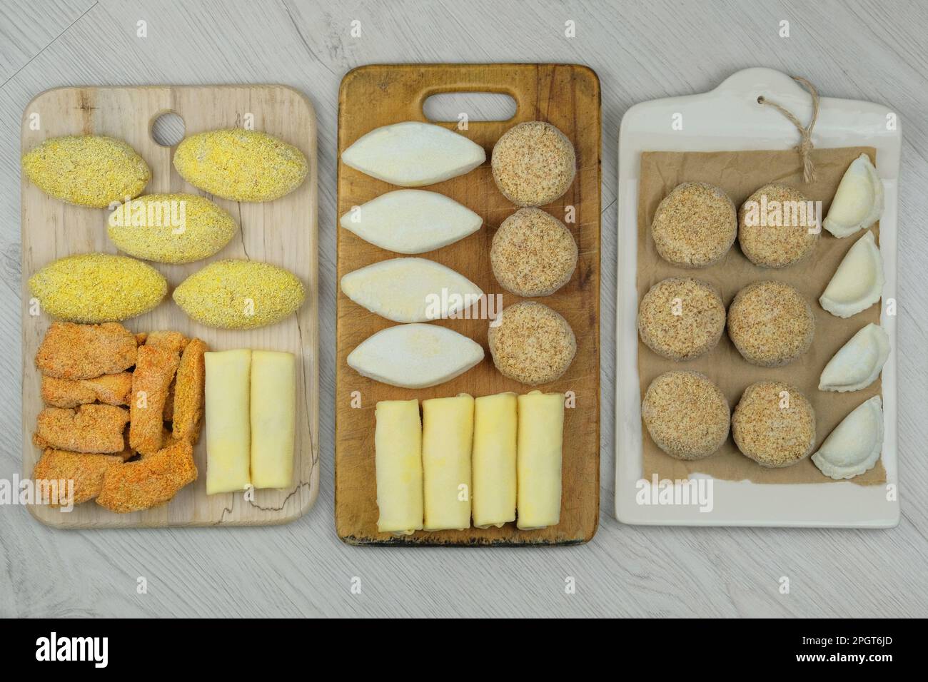 Verschiedene hausgemachte Halbfertigprodukte auf Holzbrettern. Gefrorene Schnitzel, Knödel, Nuggets. Zubereitungen aus hausgemachter Nahrung. Stockfoto