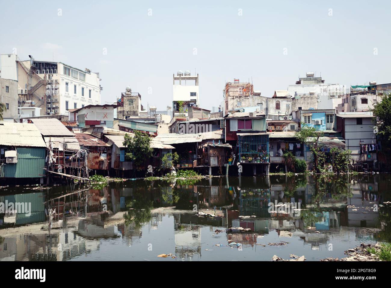 Alte Häuser auf Pfählen in den Slums von Saigon an einem Fluss voller Müll. Schlechtes Wohngebiet in Ho Chi Minh City, Vietnam, direkt am Wasser Stockfoto