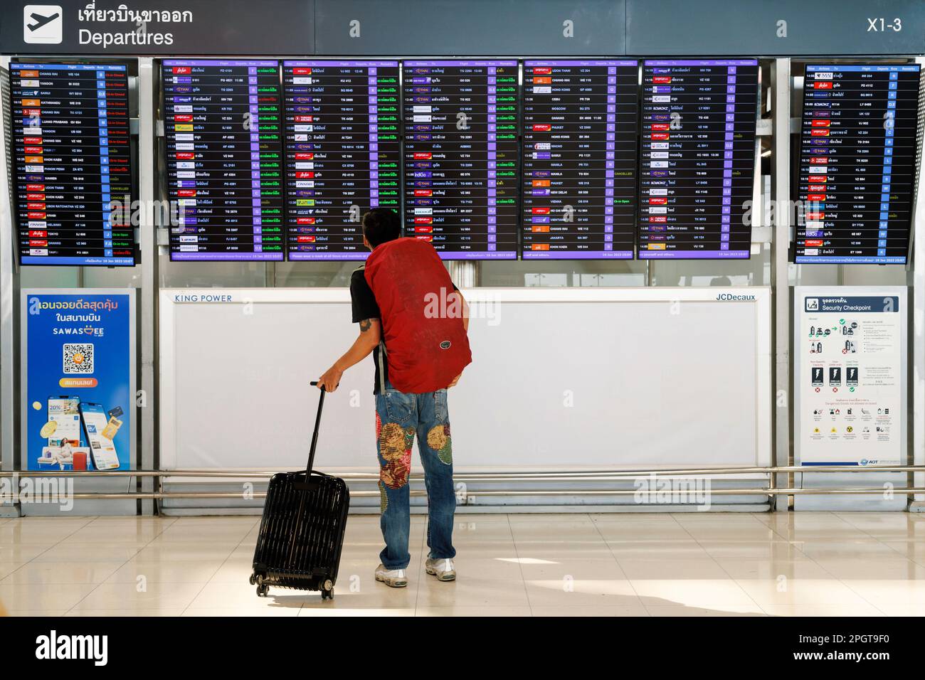 Bangkok, Thailand - 17. Februar 2023 : Reisender Rucksacktourist mit Gepäck, der auf die Abflugplantafel schaut, um den Flug bei Suvarnab zu checken Stockfoto