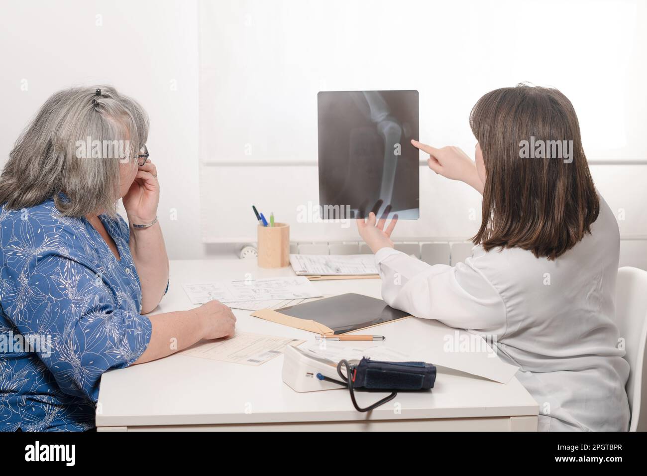 Junge Ärztin zeigt ihrem älteren Patienten ein Röntgenbild Stockfoto
