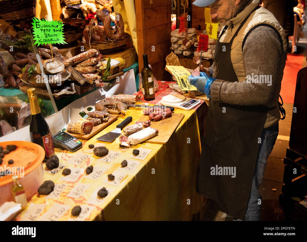 Ein Italiener in Rom macht einen Preisschild für seinen Stand, wo er Schinken und andere italienische Fleischspezialitäten verkauft. Es ist Nacht und direkt vor der Tür Stockfoto