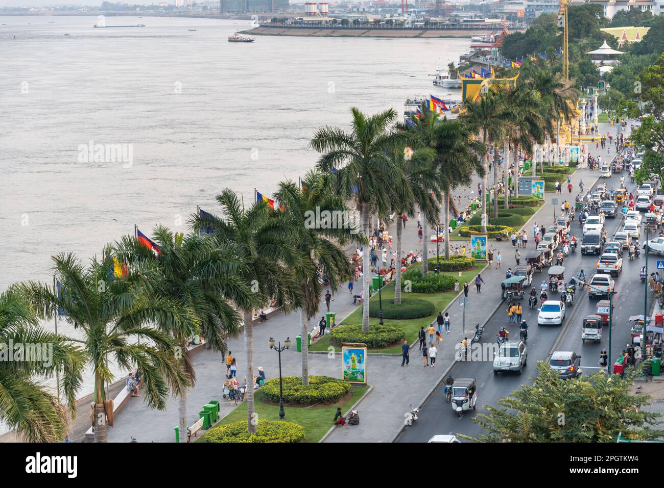 Viele kambodschanische Autos, Motorräder und Khmer Menschen bei Sonnenuntergang, geschäftigste Tageszeit. Sisowath Quay, eine beliebte Strip und Fußgängerzone, Leute und Familien CO Stockfoto