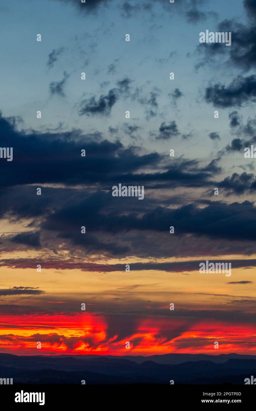 Bewölkter Himmel bei Tagesanbruch. Wolkenformationen, die von den leuchtenden Farben des Sonnenuntergangs erleuchtet werden. Blauer Himmel im Hintergrund mit Kopierbereich. Johannesburg, Stockfoto