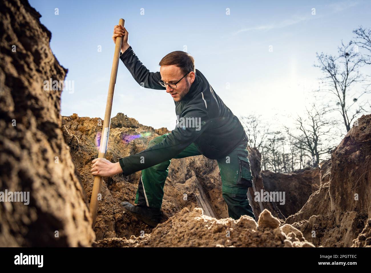 Arbeiter in einem großen Loch, der mit einer Schaufel gräbt Stockfoto