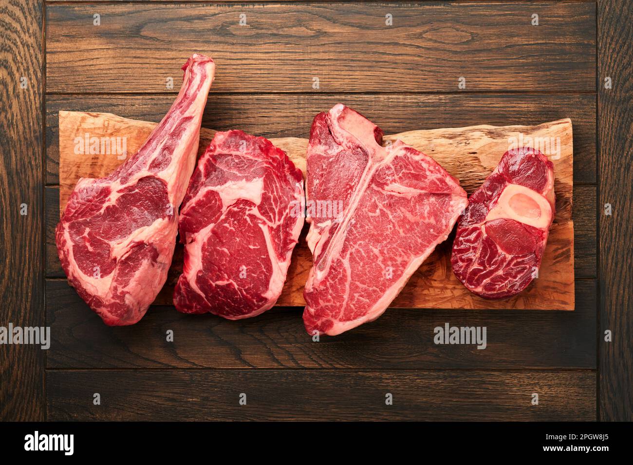 Rohe Prime Steaks. Auswahl an frischen schwarzen angus Prime Steaks T-Bone, New York, Ribeye, Striploin, Tomahawk Schneidebrett auf schwarzem oder dunklem Hintergrund Stockfoto