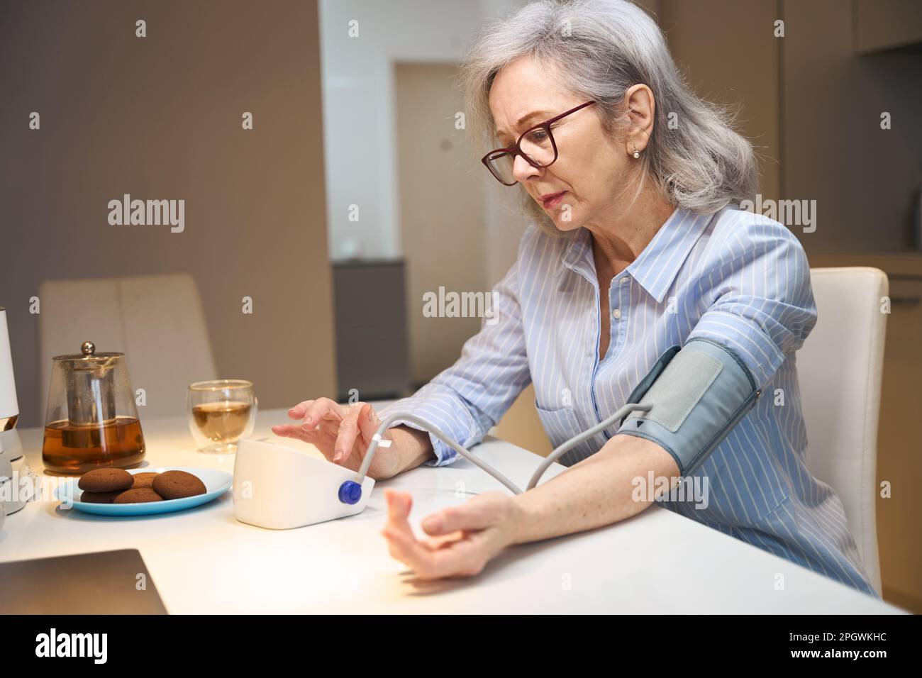 Besorgte ältere Dame misst ihren Blutdruck mit einem Tonometer Stockfoto