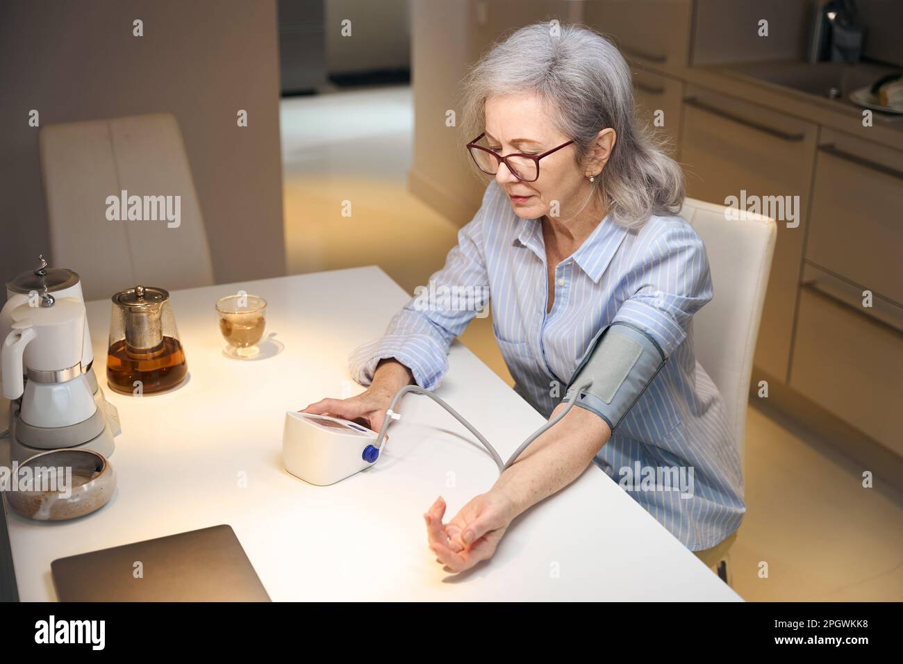 Einsame Rentnerin misst ihren Blutdruck mit einem modernen Tonometer Stockfoto