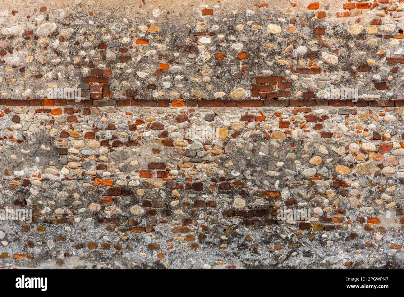 Wandtextur mit Putz und freiliegendem rotem Mauerwerk und runden Flusssteinen, Geometrie mit horizontaler Ziegelreihe. Hintergrund mit Kopierbereich Stockfoto