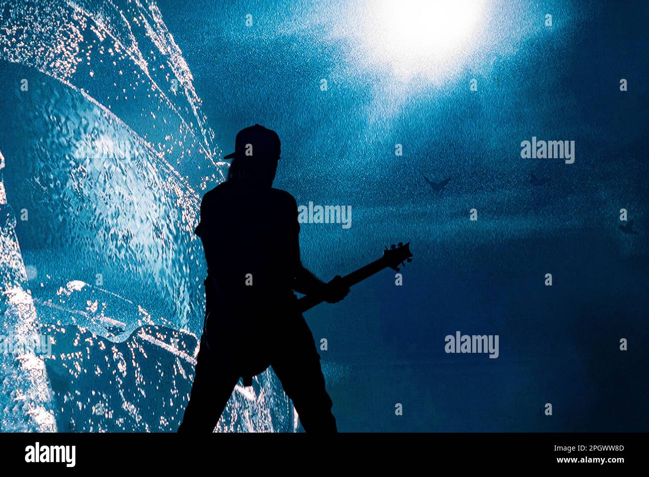 Die Silhouette des männlichen Gitarrenmanns im Hintergrund bei einem Konzert Stockfoto