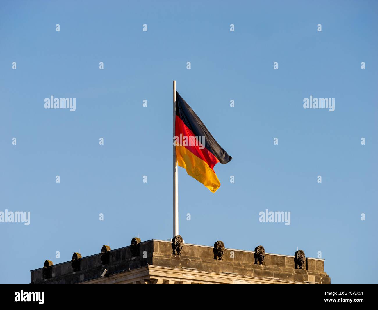 Deutsche Flagge auf dem Reichstag in Berlin. Nahaufnahme des Symbols des Landes Deutschland. Der Himmel im Hintergrund ist klar und blau. Stockfoto