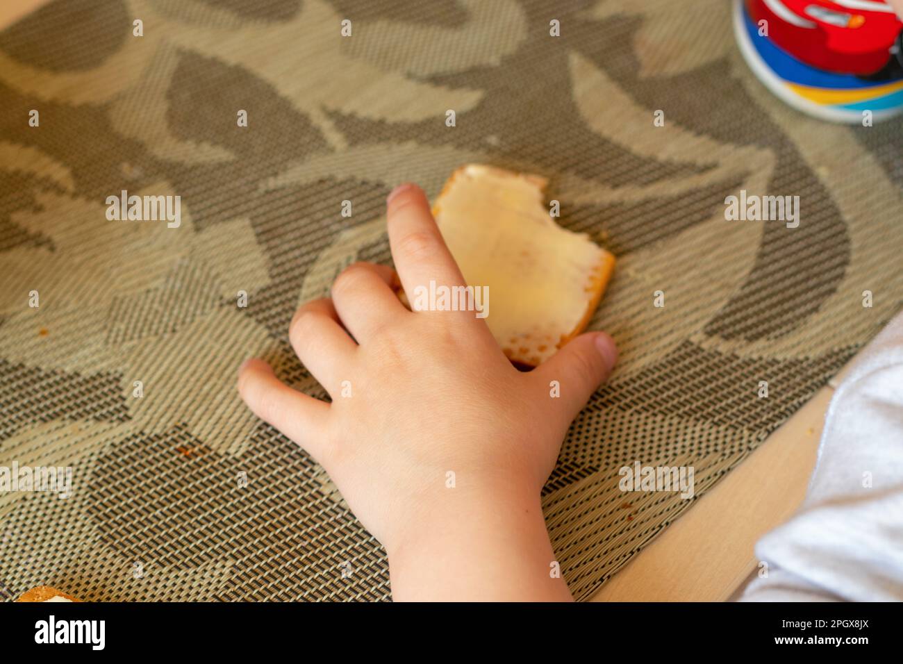 Kinderhände und Kekse mit Butter auf dem Tisch Stockfoto