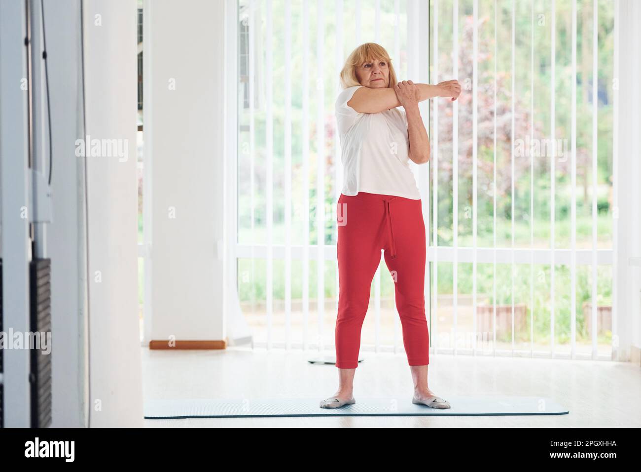 Positive Seniorin in Sportkleidung im Innenbereich tagsüber beim Training Stockfoto