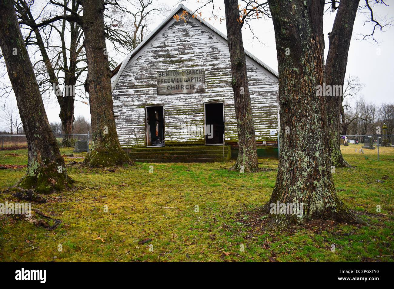 Dallas County, MO, USA, 24. März 2023. Ein altes, verlassenes Kirchengebäude steht neben einem Friedhof. Benton Branch Freewill Baptist Stockfoto