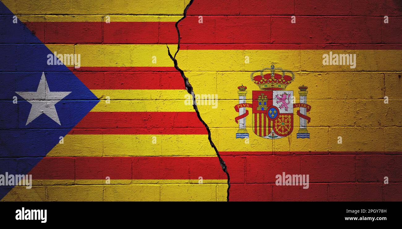 Gerissene Betonblockwand mit einer katalanischen Flagge auf der linken Seite und einer spanischen Flagge auf der rechten Seite. Stockfoto