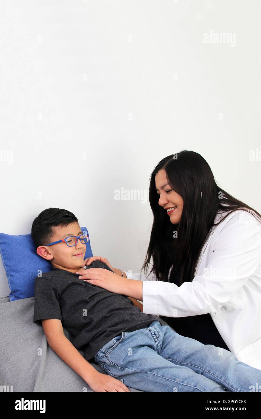 Latina Kinderärztin untersucht ihren 6-jährigen Jungen auf Halsschmerzen durch Mandelentzündung oder Pharyngitis, die Husten verursachen Stockfoto