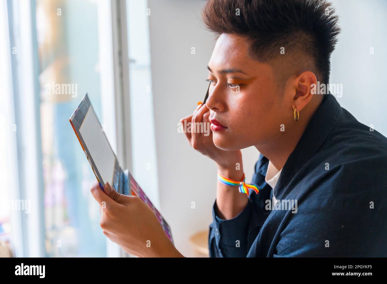 Ein Mann trägt Make-up auf und sieht sich eine Tablette an Stockfoto