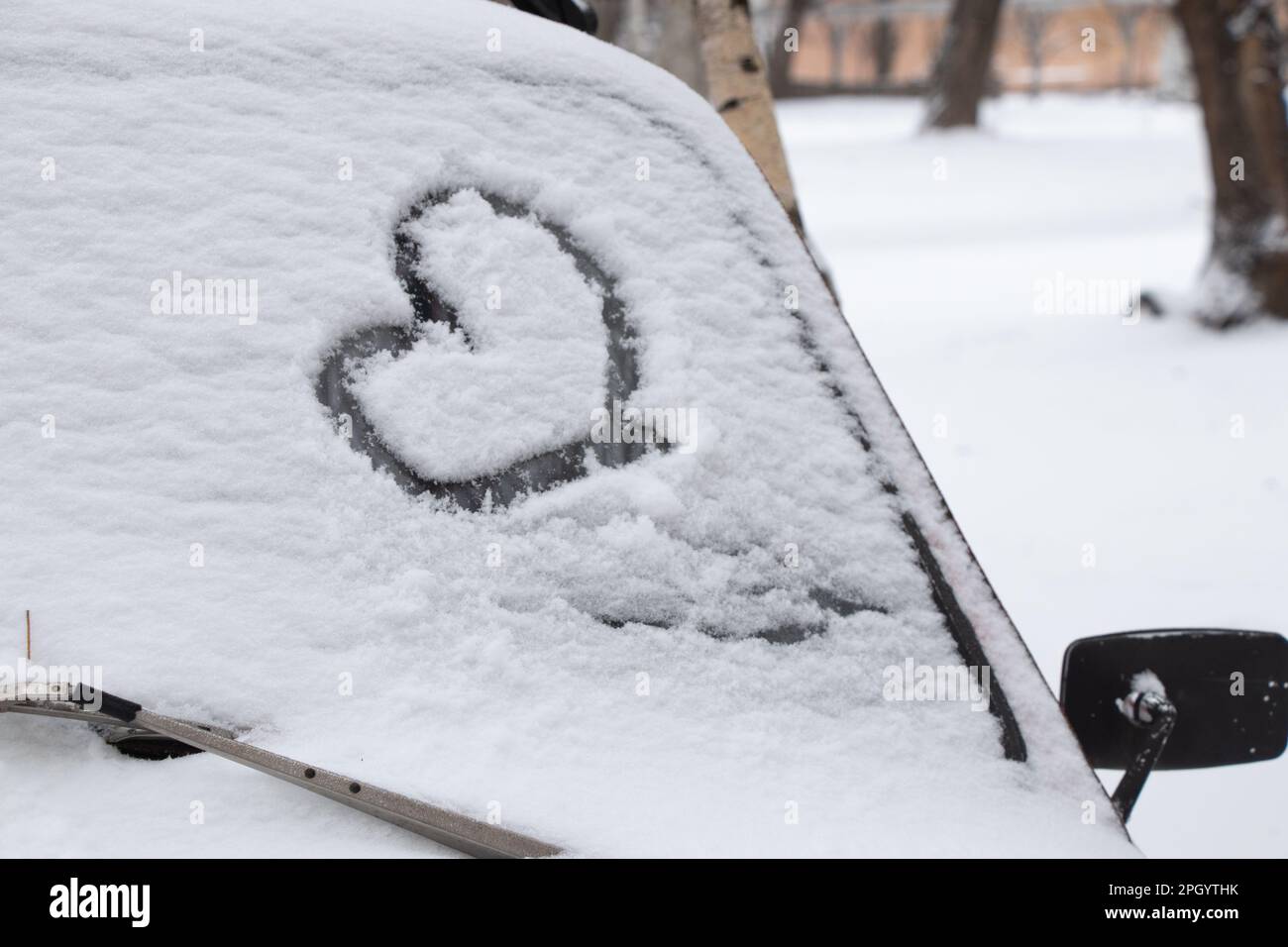Das Herz wurde im Schnee auf einem Auto gemalt, das im Januar auf dem Hof geparkt hat Stockfoto