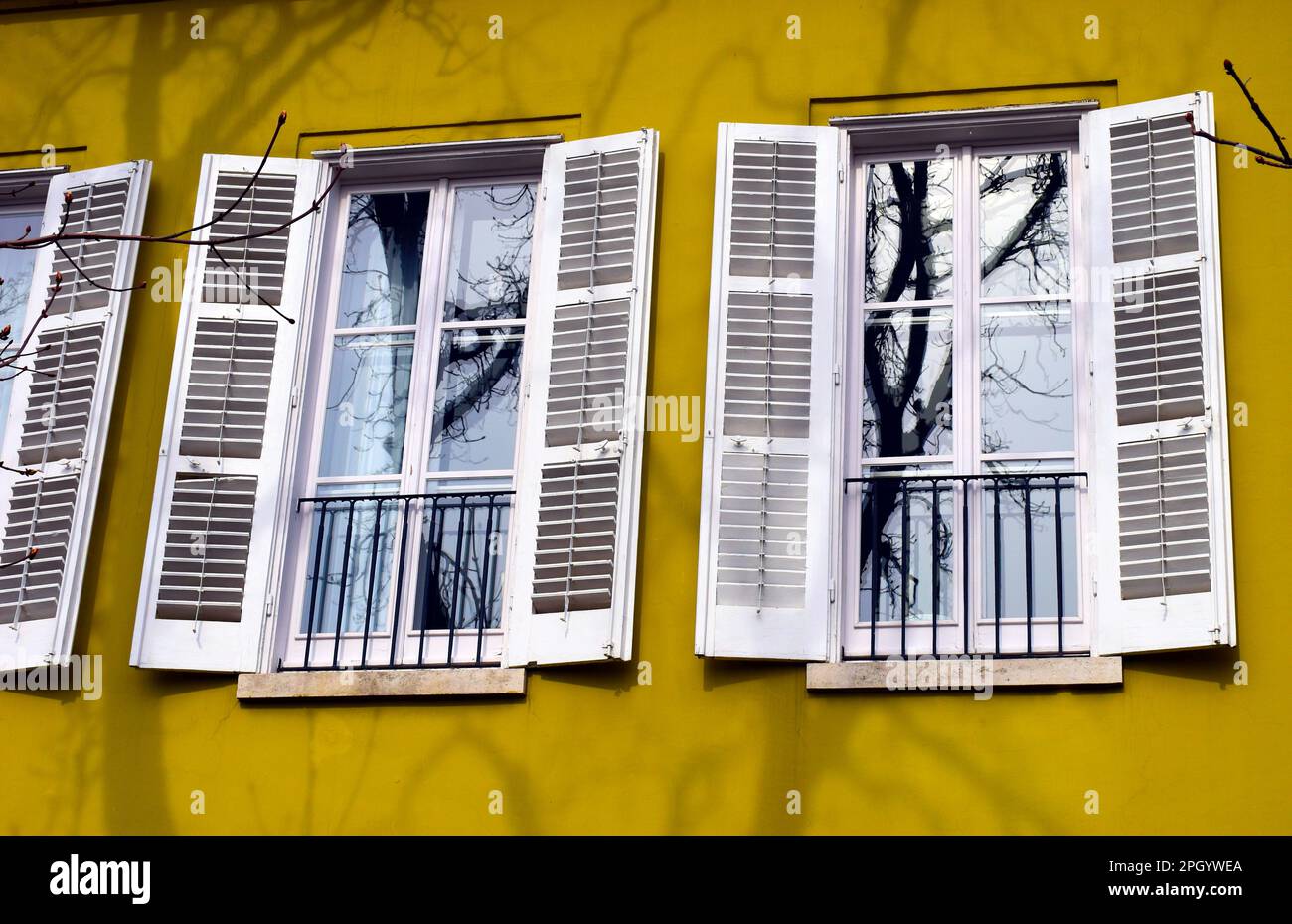 Gelbes Stuckhaus mit Außenfassade. Kleiner französischer Balkon und Glastür. Hausbesitzkonzept. Horizontale Stahlbalustrade. Metallstangen Stockfoto