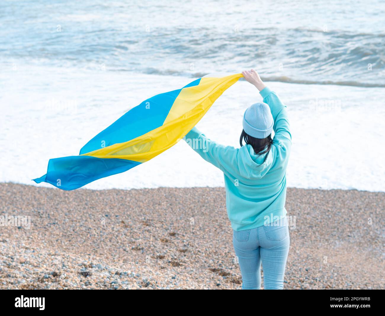 Braune Frau in blauem Hoodie und blauem Hut mit ukrainischer Nationalflagge, patriotisches Konzept Stockfoto