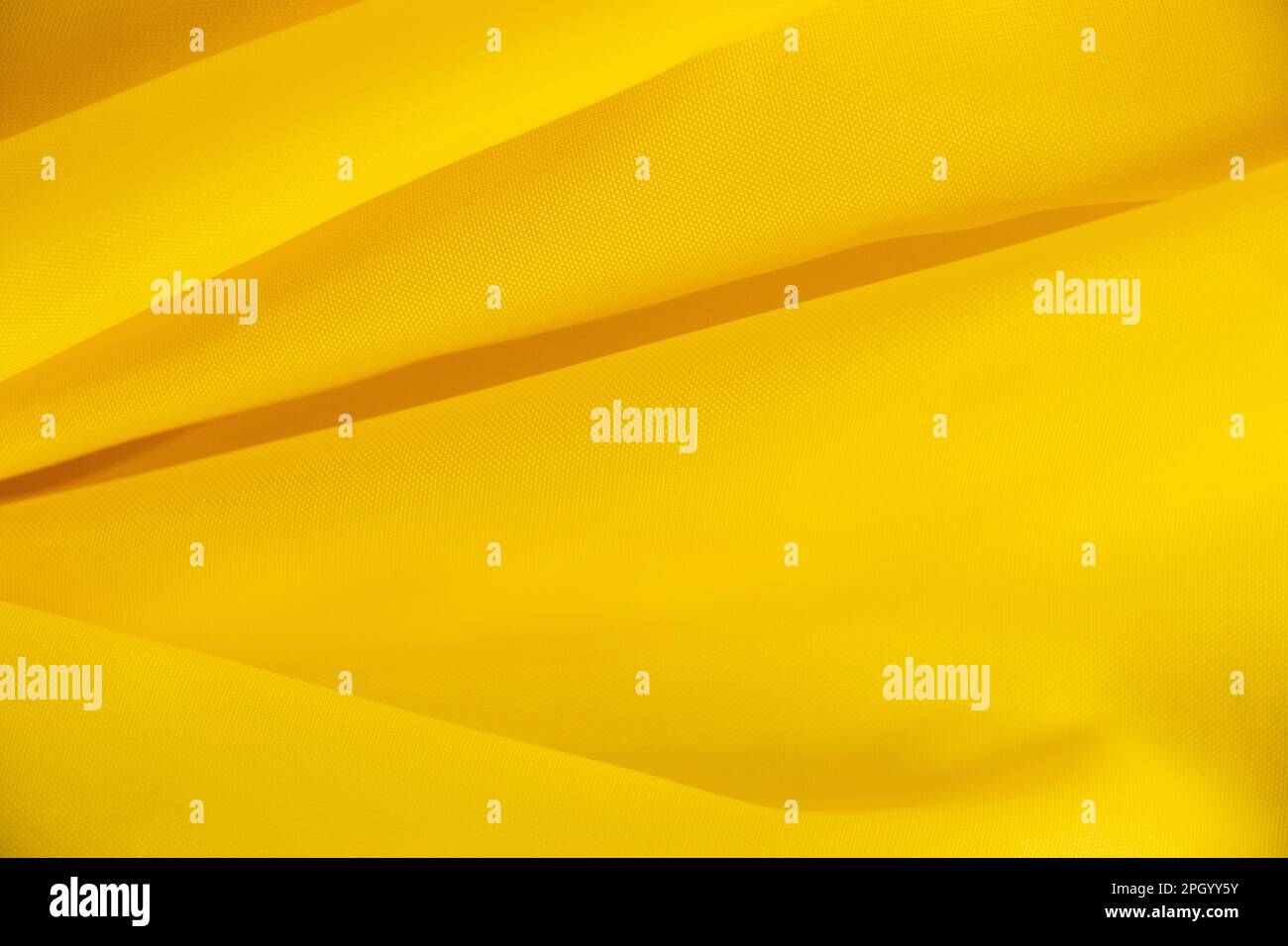 Gelber, zerknitterter Stoff aus Seide als Nahaufnahme des Hintergrunds Stockfoto