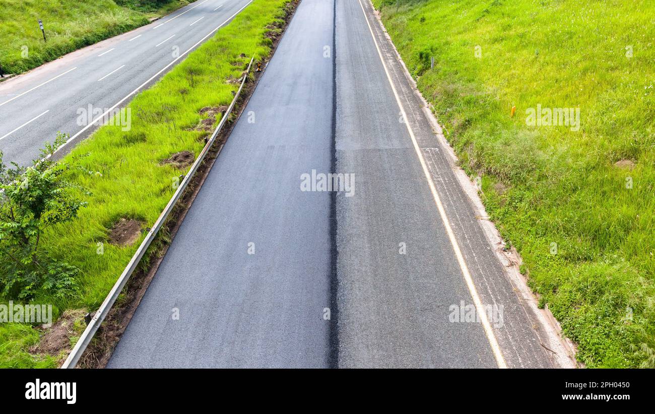 Straßenroute mit einer Spur mit neuem Asphaltteer zur Verbesserung der Fahrzeugsicherheit. Overhead-Foto. Stockfoto
