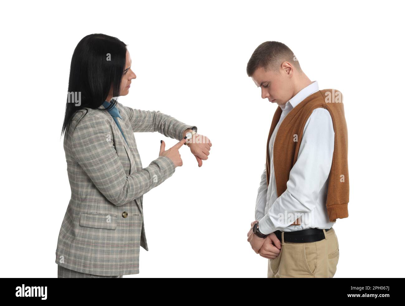 Eine Geschäftsfrau, die auf die Armbanduhr zeigt, während sie einen Angestellten wegen Verspätung vor weißem Hintergrund beschimpft Stockfoto