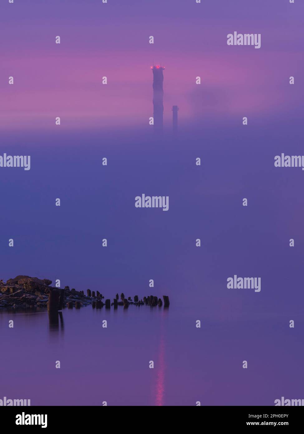 Der Morgennebel erhebt sich langsam über den Fluss Gothenburgs und offenbart die Silhouetten eines Schornsteins, während die Morgendämmerung am Horizont bricht. Stockfoto