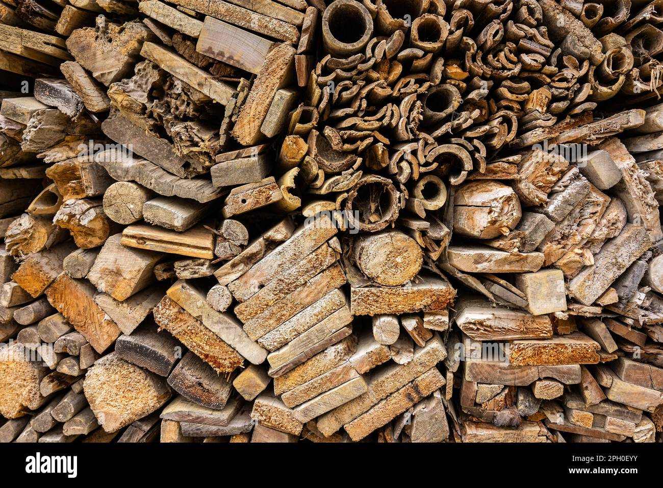 Hintergrund von gestapelten Holzbrettern unterschiedlicher Formen. Vollständige Oberflächenstruktur der Endstücke von Holzstücken in Brauntönen. Stockfoto