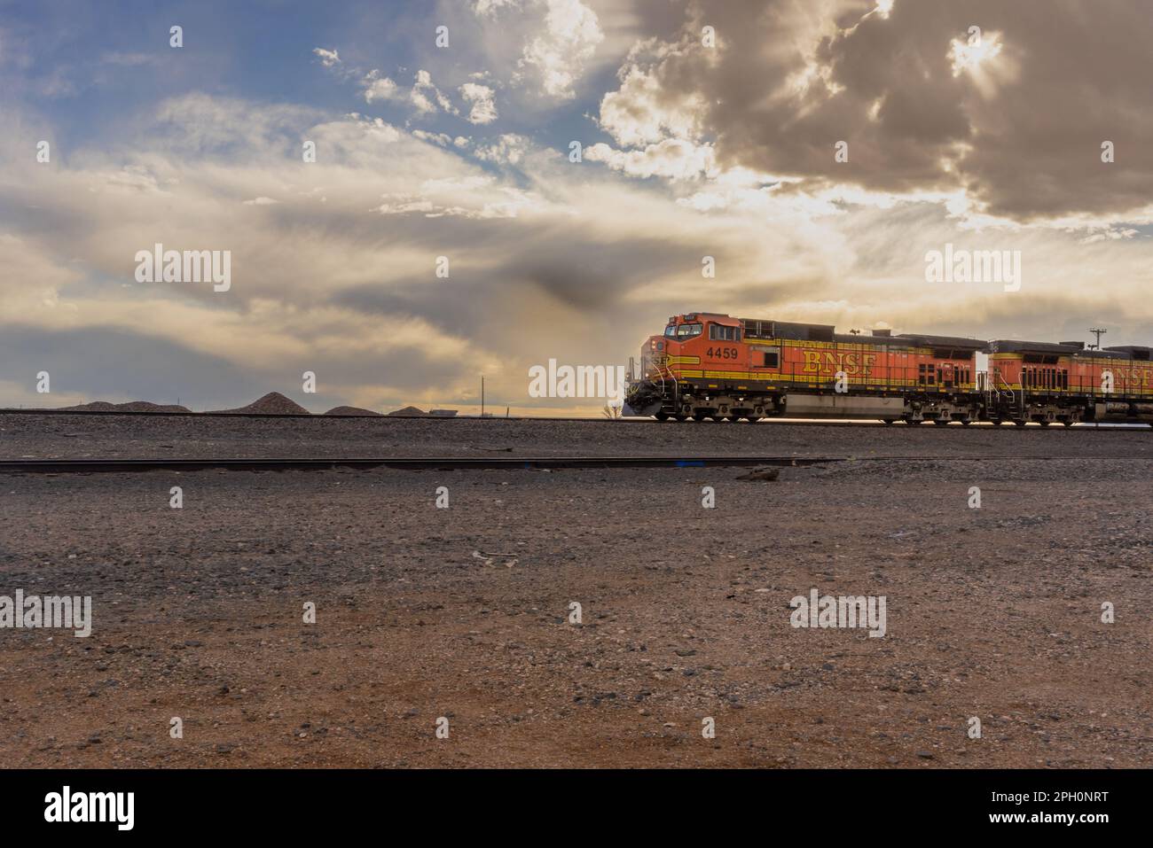 Ein leuchtend orangefarbener BNSF Railway-Güterzug fährt durch die kalte Wüste von Yeso, New Mexico. Stockfoto
